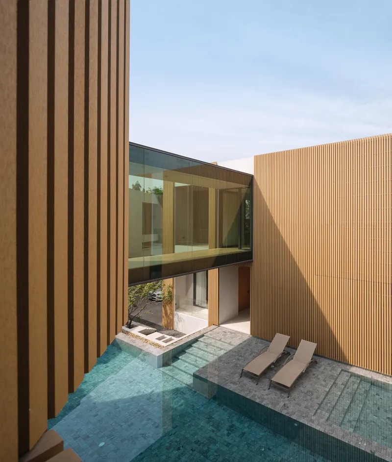 View from upper level showing the glazed bridge spanning above submerged pool steps and lounge chairs