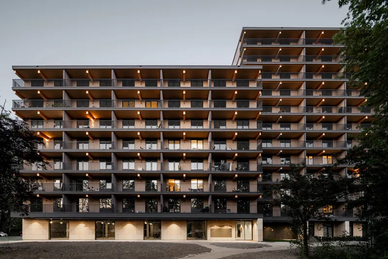 Layered timber and concrete balcony facade with recessed terraces illuminated at dusk