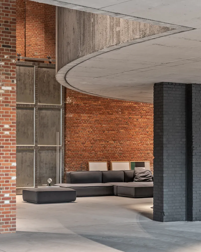 Sweeping concrete ceiling edge meeting exposed brick wall above seating area with painted brick column