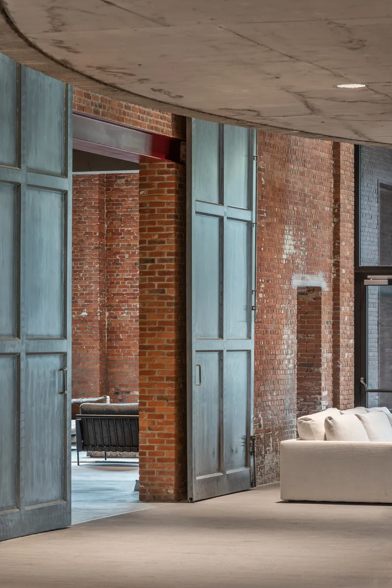 Tall steel-framed sliding doors with patinated finish between exposed brick piers