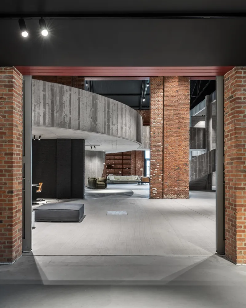 View through brick portal frame revealing cantilevered concrete stair and double-height loft space