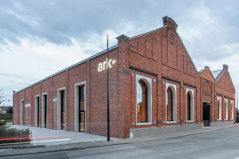 Corner view of the red brick facade with arched windows and illuminated signage at dusk
