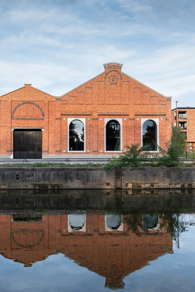 Canalside view of the red brick warehouse with its reflection in the still water