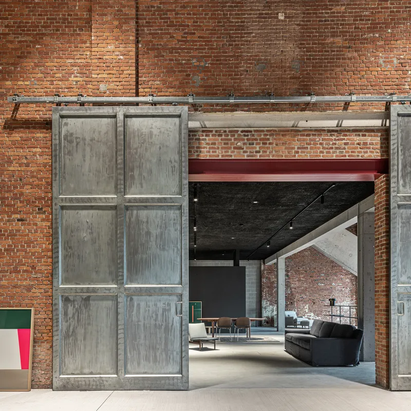 Sliding concrete panel door on overhead track against the weathered brick interior wall
