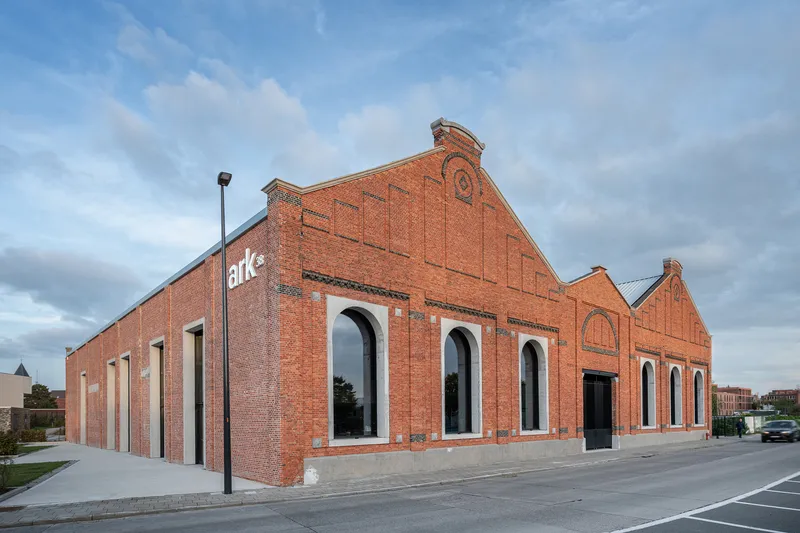 Street view of the brick facade with arched openings and stepped parapet under cloudy sky