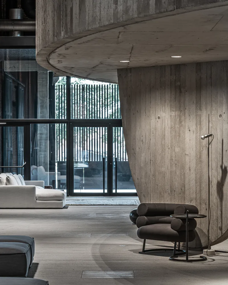 Curved concrete soffit edge meeting board-formed wall with glazed doors to exterior courtyard
