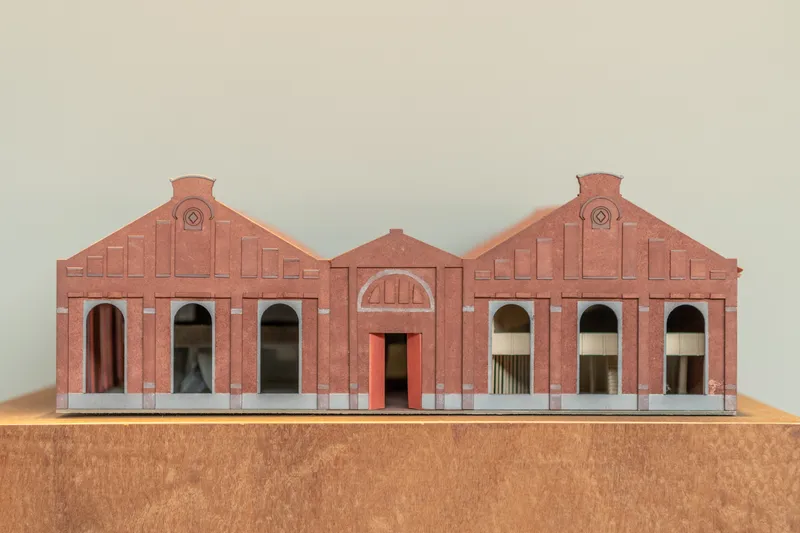 Physical model showing the symmetrical brick facade with gabled rooflines and arched openings