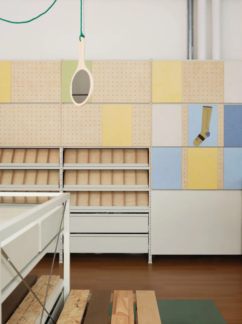 Modular pegboard wall with yellow and blue panels above timber slatted storage drawers