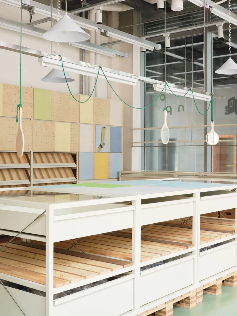 White framed display platforms beneath pendant lights suspended on green braided cords