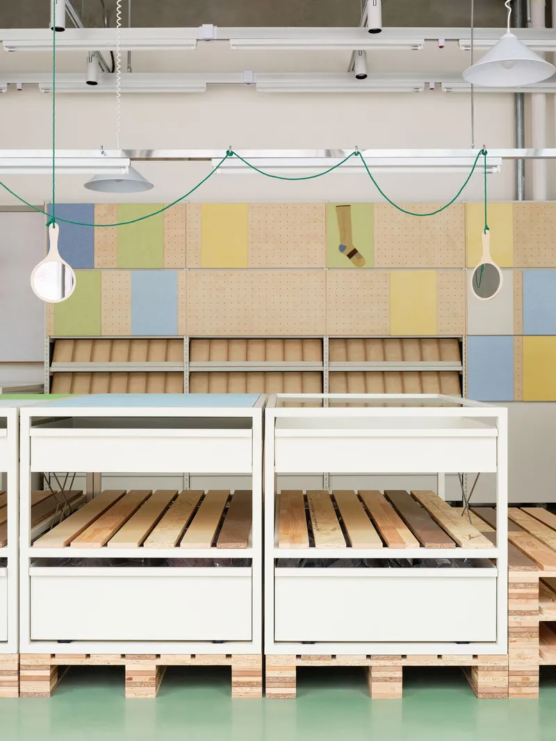 Frontal view of white powder-coated tables with slatted timber shelves on mint green rubber flooring
