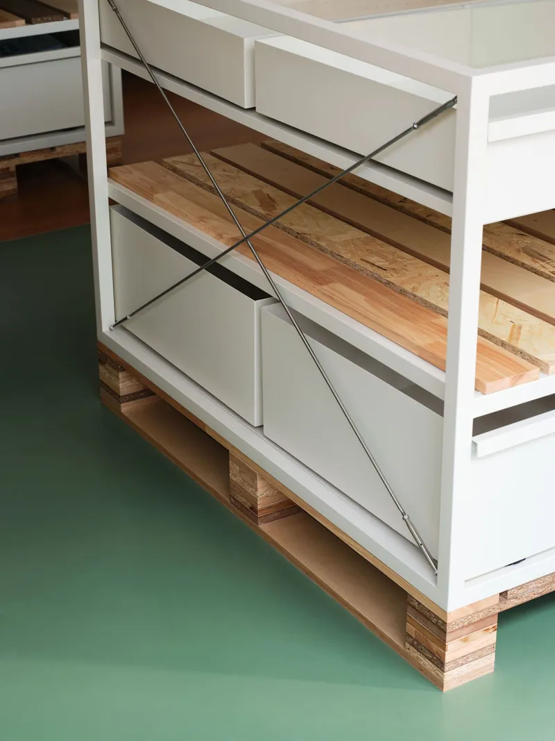 Close-up of diagonal cable tensioning system and drawer mechanism on white steel table frame