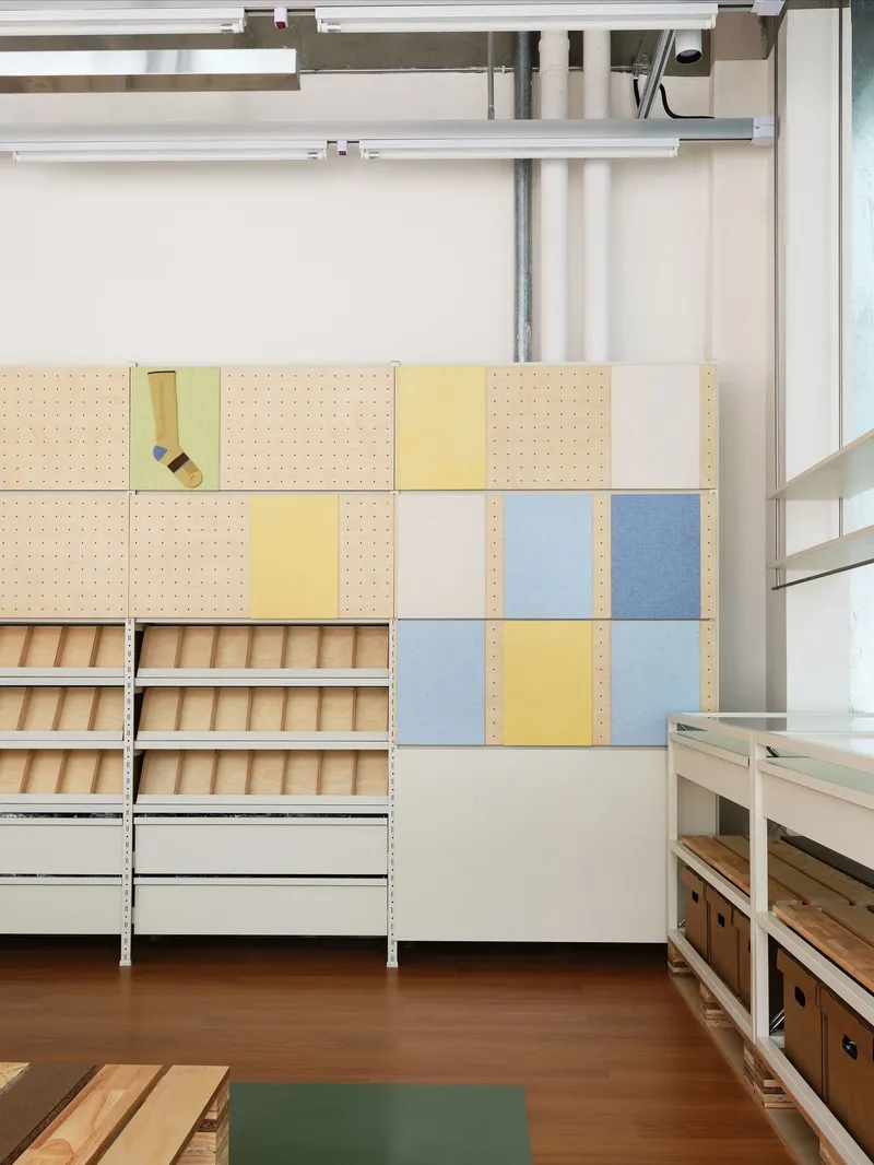 Modular storage wall with pegboard panels in pastel yellow and blue alongside open shelving units
