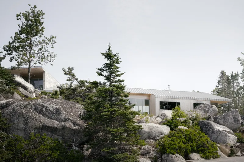 Low-slung profile with corrugated metal roof nestled among granite boulders and evergreen trees