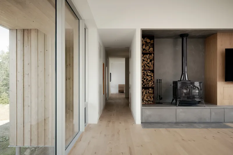 Interior corridor with wood-burning stove in concrete hearth and stacked firewood storage