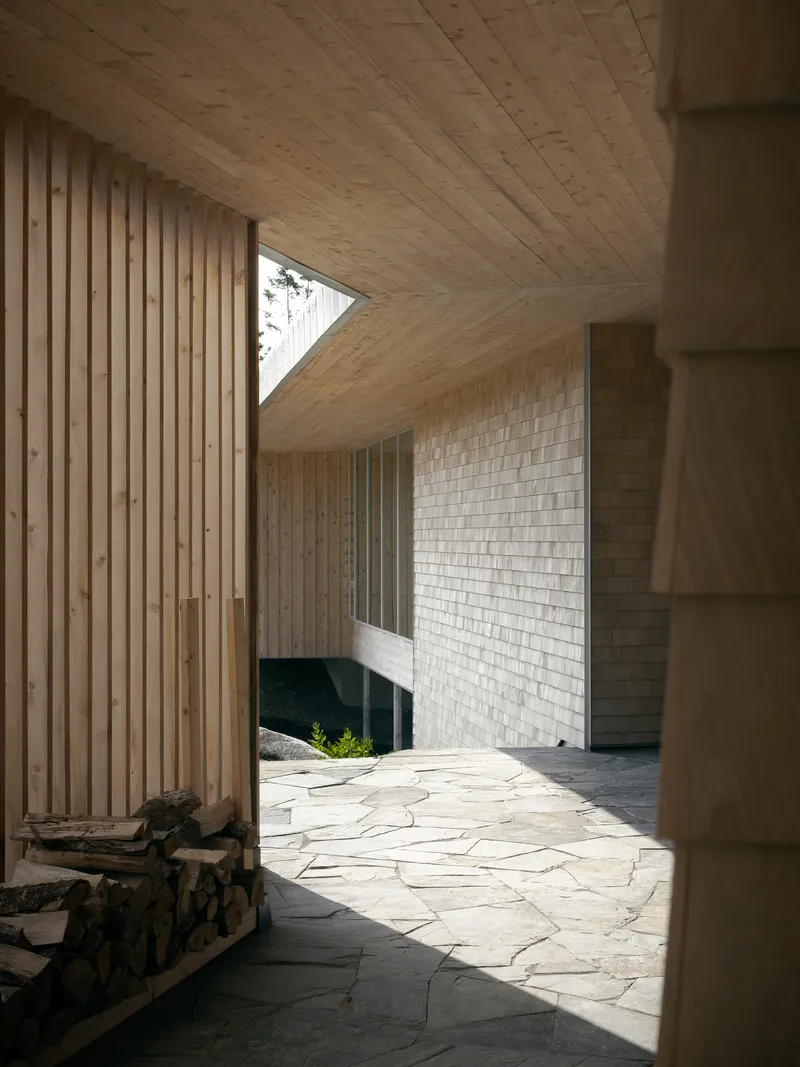 Covered outdoor terrace with irregular stone paving and vertical timber screen wall