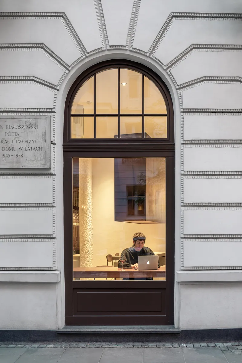 Arched doorway in rusticated stone facade with a person working inside at dusk