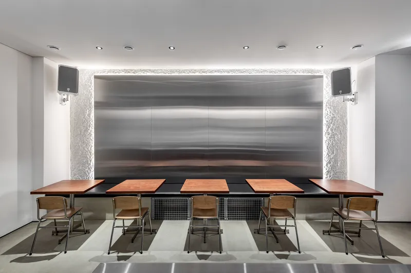 Boardroom with alternating stone floor tiles and horizontal banded metal wall panels behind the table