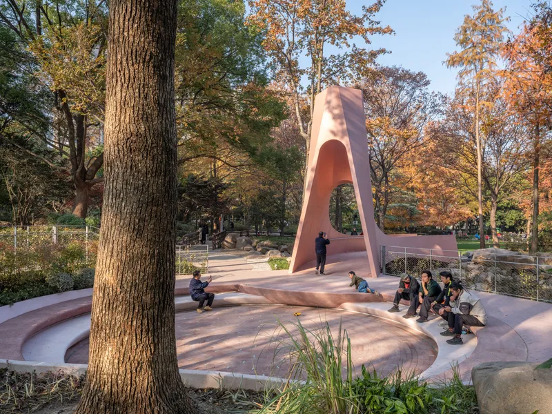 Curved arch structure framing a public park with visitors seated on tiered concrete platforms