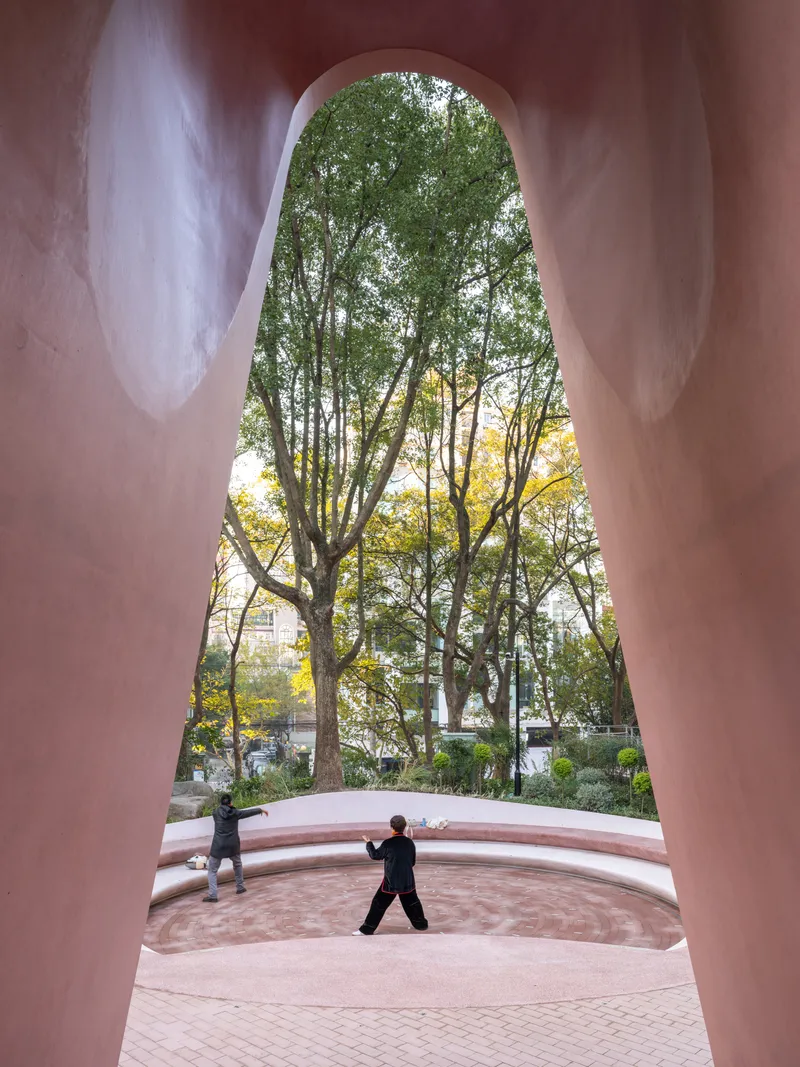 View through the tall arched opening framing a person at the amphitheater with trees beyond