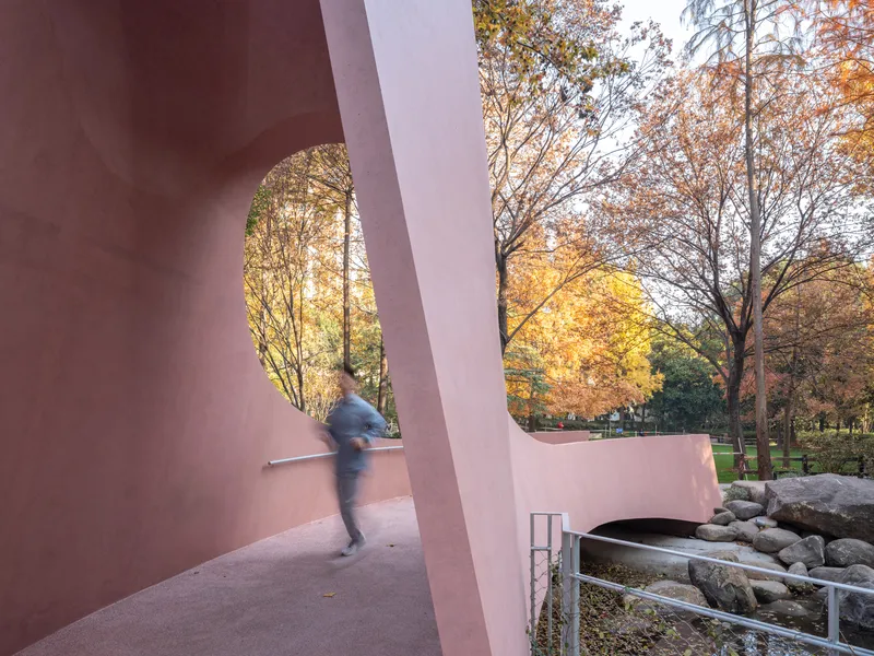 Interior walkway through the gateway with a blurred figure passing beside the curved parapet at dusk