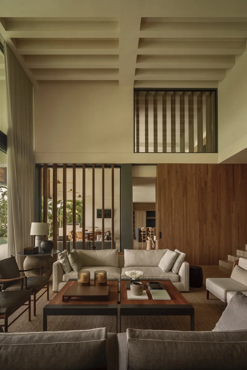 Living room with exposed beam ceiling and timber slat screens framing mezzanine levels above