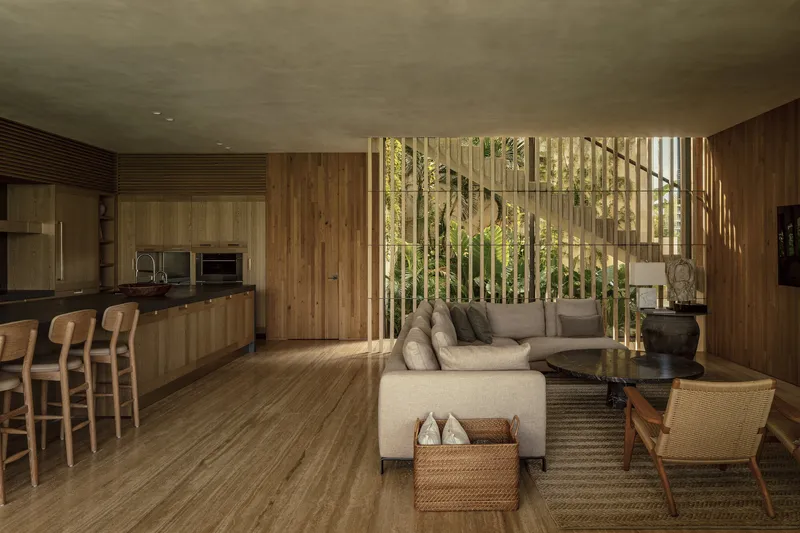 Open living and kitchen space with vertical wood screen filtering daylight from garden beyond