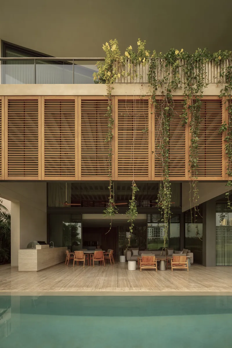 Covered poolside terrace with horizontal timber louver screen and cascading vines overhead