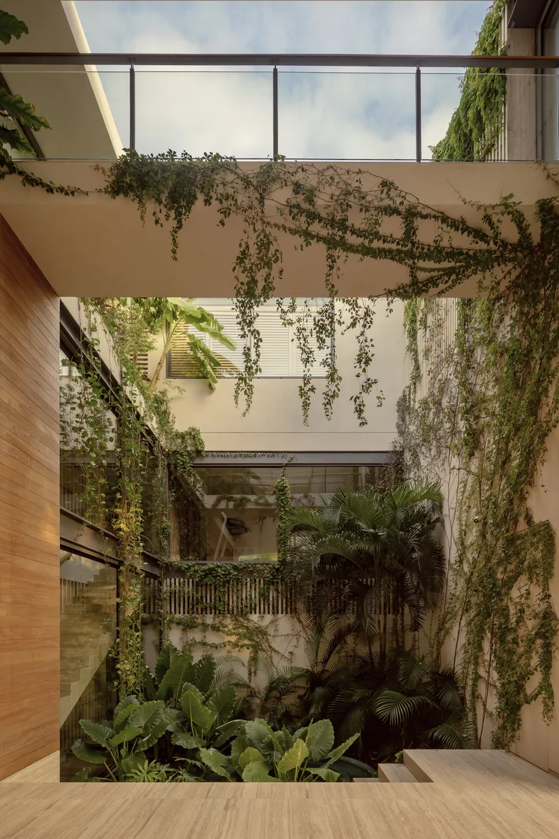 Open-air courtyard with cascading vines covering white walls and timber floor opening to tropical plantings