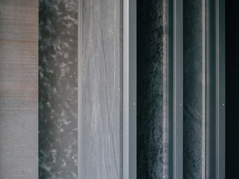 Overhead view of parallel material bands including concrete, dark metal panels and stone pavers