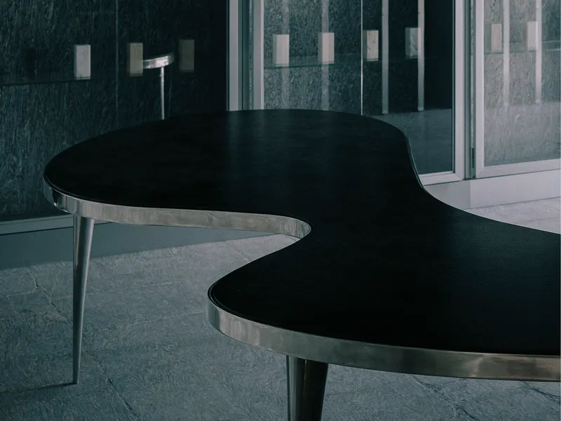 Curved black reception desk with polished metal edging beside glass partition wall