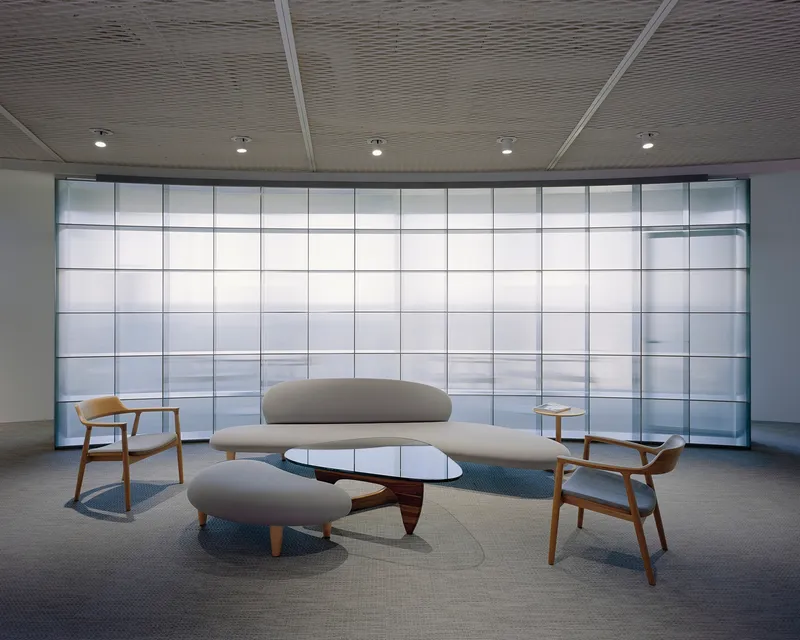 Seating alcove with curved sofa and glass coffee table facing grid patterned translucent facade