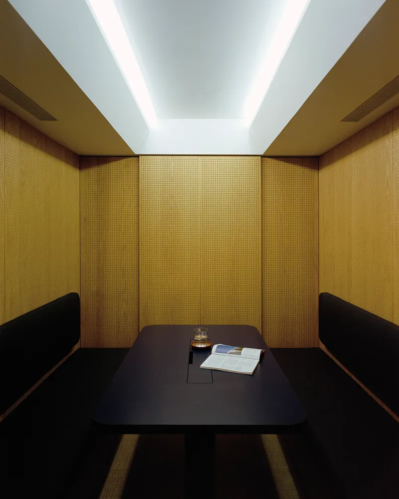 Enclosed booth with woven gold panels and recessed ceiling illumination