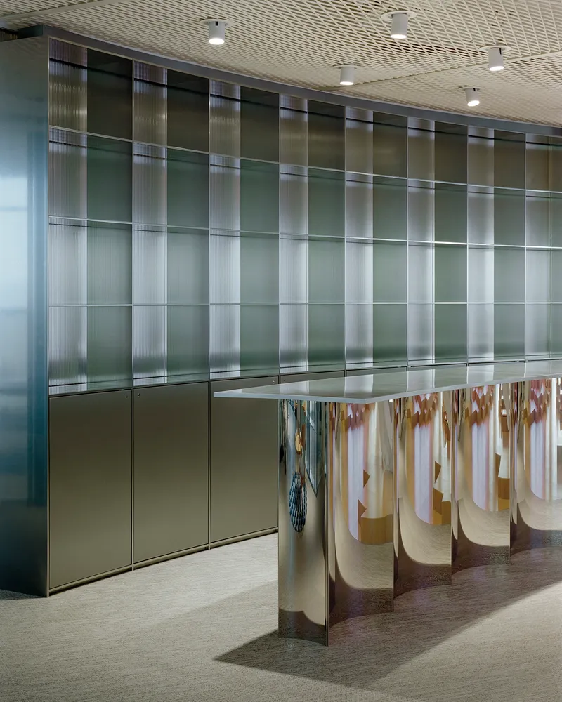Polished stainless steel reception desk before a gridded translucent wall