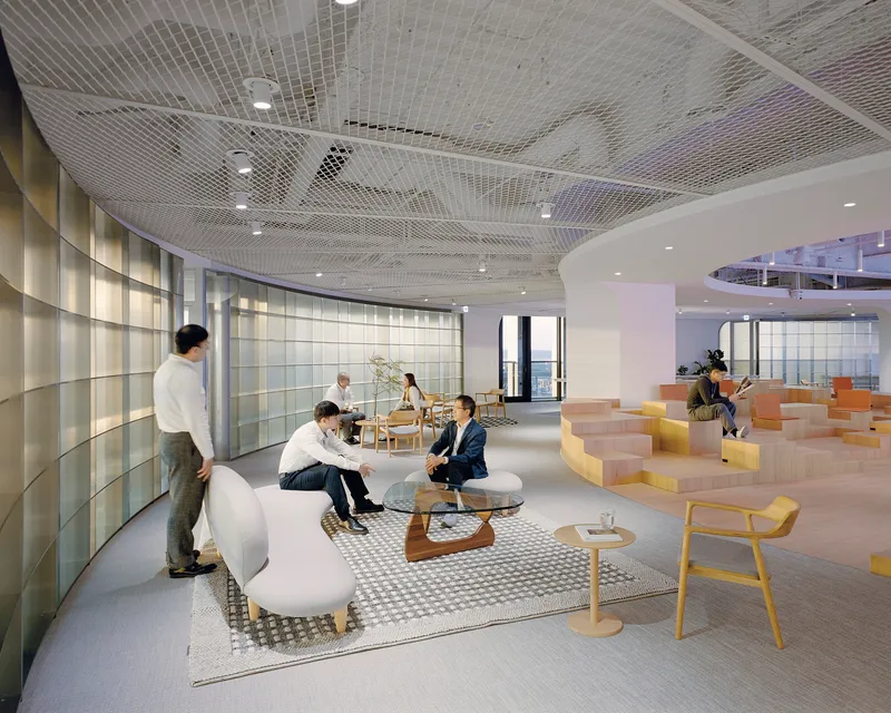 Open office lounge with mesh ceiling and stepped seating platform in use