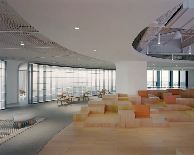 Multilevel workspace with translucent glass wall panels and scattered plywood seating modules