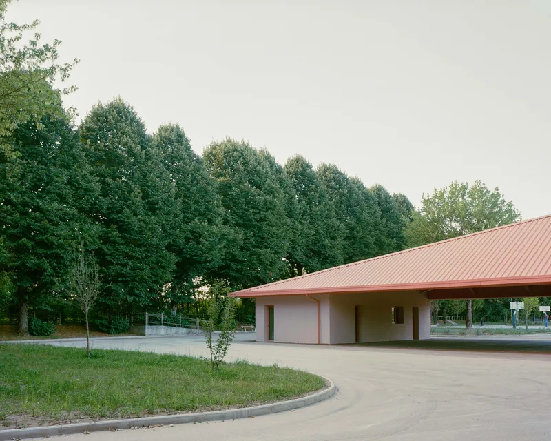 Covered portico with recessed openings and overhanging pink metal roof edge at dusk
