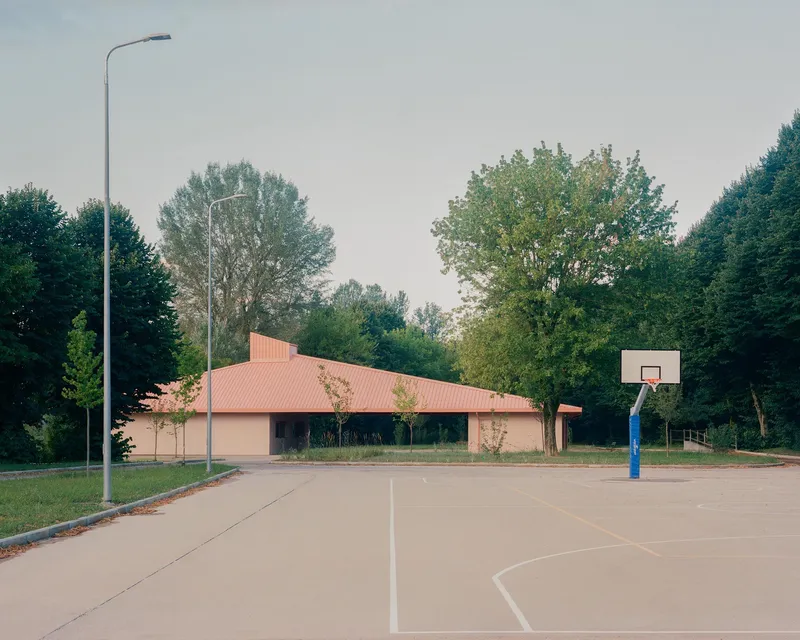 View from the adjacent basketball court showing the low-slung roof volume and street lamp