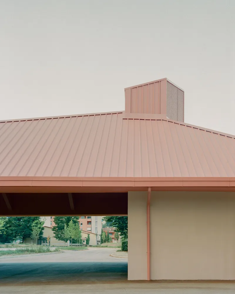 Corner view of the standing seam metal roof and perforated metal chimney under overcast sky
