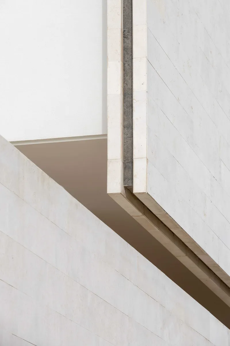 Close-up of concrete fin meeting the underside of a cantilevered slab with sloped soffit detail