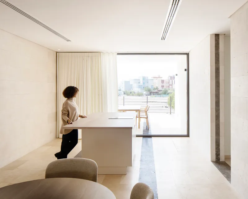 Living space with person standing at white counter facing sliding glass door to terrace beyond