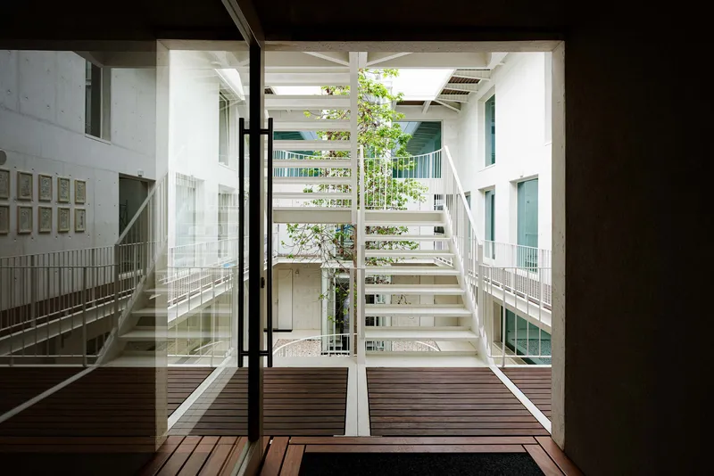 Timber deck terrace overlooking central courtyard with white steel stairs and tree canopy under skylights