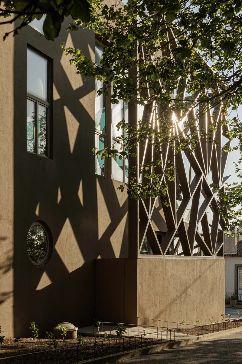 Late afternoon sunlight filtering through the lattice structure and casting geometric shadows on the plaster wall