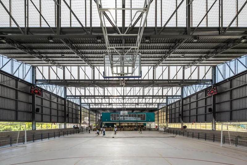 Full-height steel truss structure framing a large covered court with concrete floor