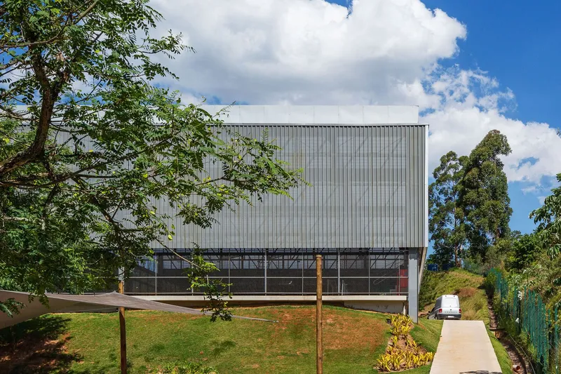 Two-story facade with vertical metal cladding and horizontal glazed strip on a sloped site