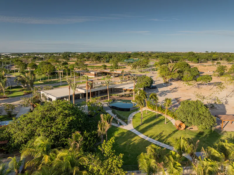 Aerial view of low-slung pavilions surrounded by palm trees and landscaped lawns at dusk