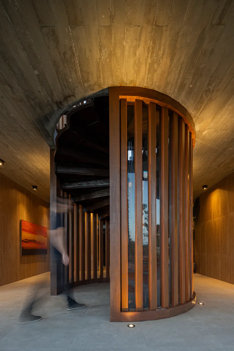 Close-up of the cylindrical timber screen with vertical slats and spiral staircase visible inside
