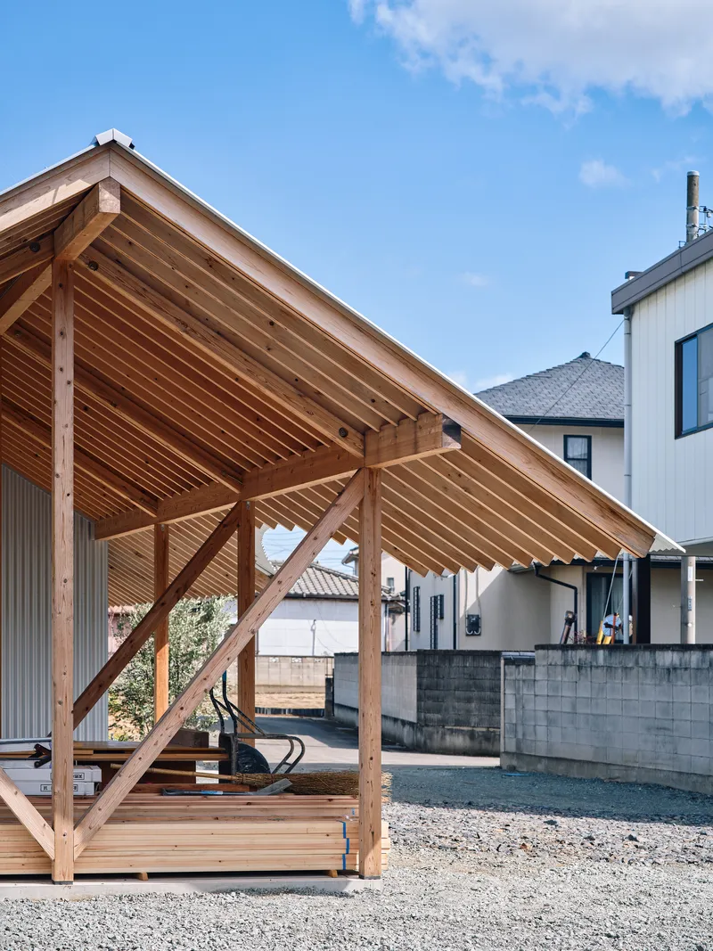 Timber-framed pavilion with exposed rafters and slatted ceiling over a gravel courtyard