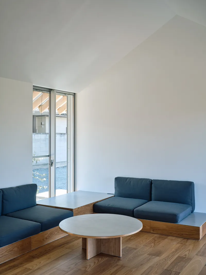 Interior seating area with built-in blue cushioned benches and low round table on timber flooring
