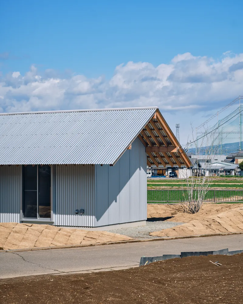 Gabled end with exposed timber louvers above corrugated grey cladding under a blue sky