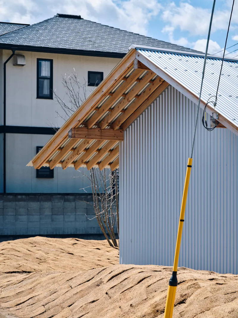 Close view of the gabled roof corner with timber slat eaves and corrugated metal walls